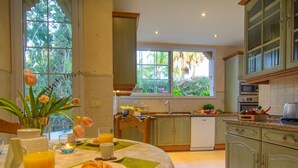 A kitchen with a dining area, featuring a breakfast setup with croissants, orange juice, and a vase of flowers. - 75m to Beach Luxury 4-Bed Villa with Heated Pool & Oasis Patio in Marbella (Marbella)