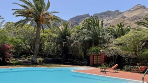 A swimming pool with clear blue water, surrounded by lush greenery and palm trees. - Country house with heated swimming pool for exclusive use between the sea and the mountains.  (Lomo de San Pedro)