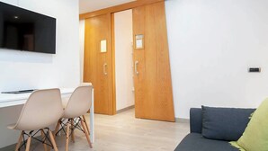 Une chambre moderne équipée d’un bureau, de deux chaises, d’un canapé et d’une armoire à portes coulissantes.