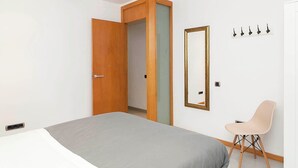 Une chambre à coucher avec un lit, une chaise, une armoire et un miroir.
