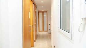 Un couloir avec des portes en bois, un téléphone et une fenêtre.