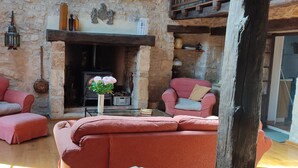 A cozy room with stone walls, a fireplace, and two red sofas. - Charming holiday cottage in the heart of the Périgord Noir (Plazac)