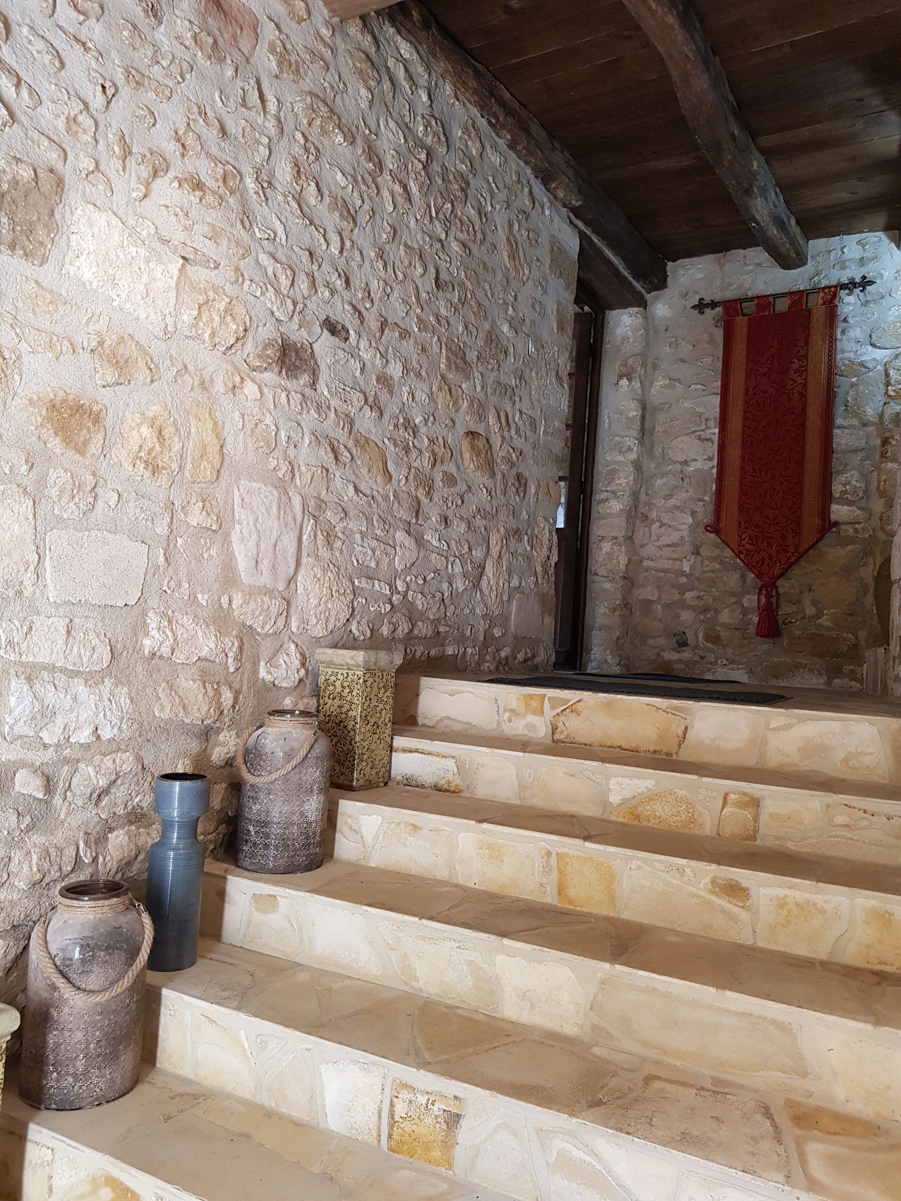 Un escalier en pierre avec un tissu rouge suspendu au mur.