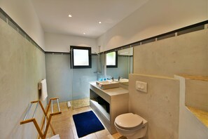 Une salle de bain moderne équipée de toilettes, d’un lavabo et d’un espace douche.