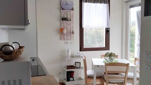 A kitchen with a microwave, a clock, and a window with curtains. - Villetta Gelsomino, in Bardolino Calmasino villa in residence with swimming pools. (Calmasino)