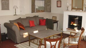 Una sala de estar con un sofá, una mesa, dos sillas, una chimenea y un televisor.
