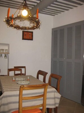Zona pranzo con tovaglia a righe, sedie di legno, lampadario e una porta chiusa sullo sfondo.