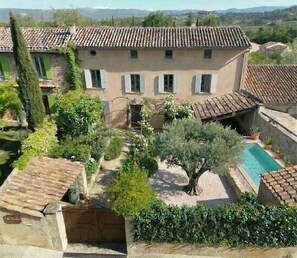 Una villa con piscina, rodeada de vegetación y vistas al campo.