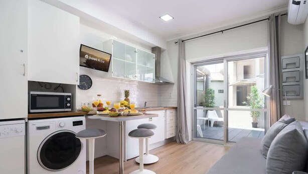A modern kitchen with a washing machine, microwave, and a breakfast bar with stools.