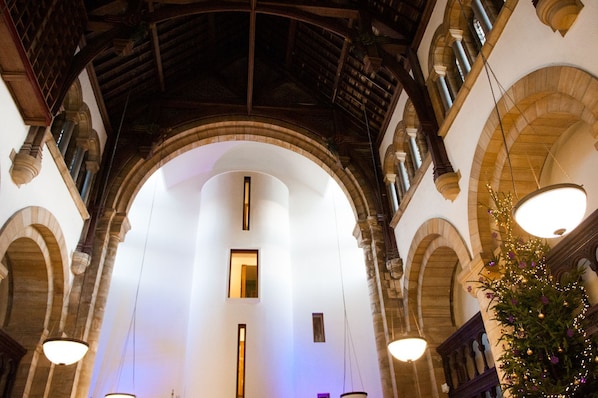An interior with a high arched ceiling, stone columns, and a central open space. - Raven Wing 11 Highland Club (Loch Ness)