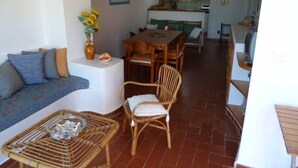 A living room with a sofa, a wicker table, and a dining area with a table and chairs.