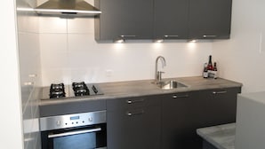 Una cocina moderna con armarios oscuros, electrodomésticos de acero inoxidable y un horno empotrado.
