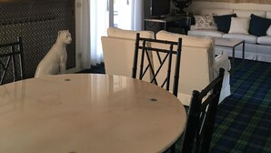 Une pièce comprenant une table ronde, des chaises, un canapé, un téléviseur et un lustre décoratif.