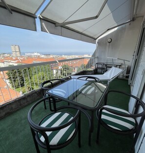 A balcony with a table and chairs, a view of the city, and a building in the distance. - Penthouse in the center with sea view (Trieste)