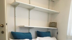 Un lit avec une literie blanche et bleue, une tête de lit blanche et une étagère au-dessus du lit.
