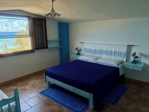 A bedroom with a bed, two bedside tables with lamps, a window with a view, and a chair.