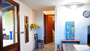 A hallway with a wooden door, a chair, a table with a plate, and a wall clock. - House "The two Lapwing" (semi-detached portion) (Marina di Tertenia, Tertenia (OG))