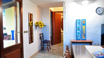 A hallway with a wooden door, a chair, a table with a plate, and a wall clock.