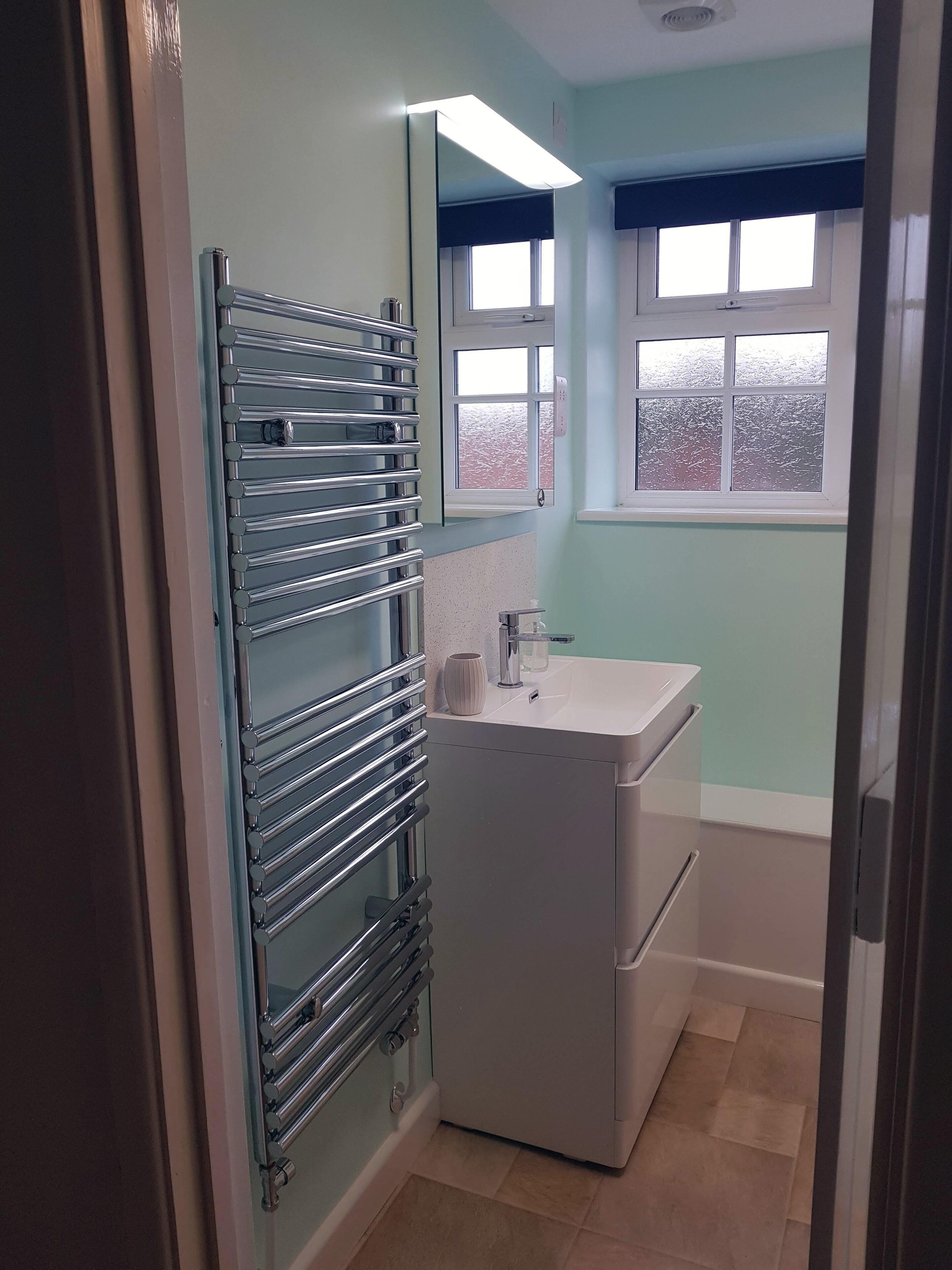 A bathroom with a glass shower enclosure, a white sink, and a window with frosted glass.