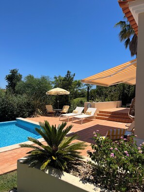 A poolside area with lounge chairs, a table, and umbrellas.