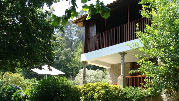 A stone building with a balcony, surrounded by lush greenery and a garden. - Cete: house / villa - Cête (Cête)