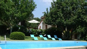 A swimming pool with blue lounge chairs and a small umbrella. - Cete: house / villa - Cête (Cête)