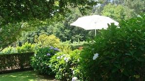 A garden with a white umbrella, lush greenery, and a well-maintained lawn. - Cete: house / villa - Cête (Cête)