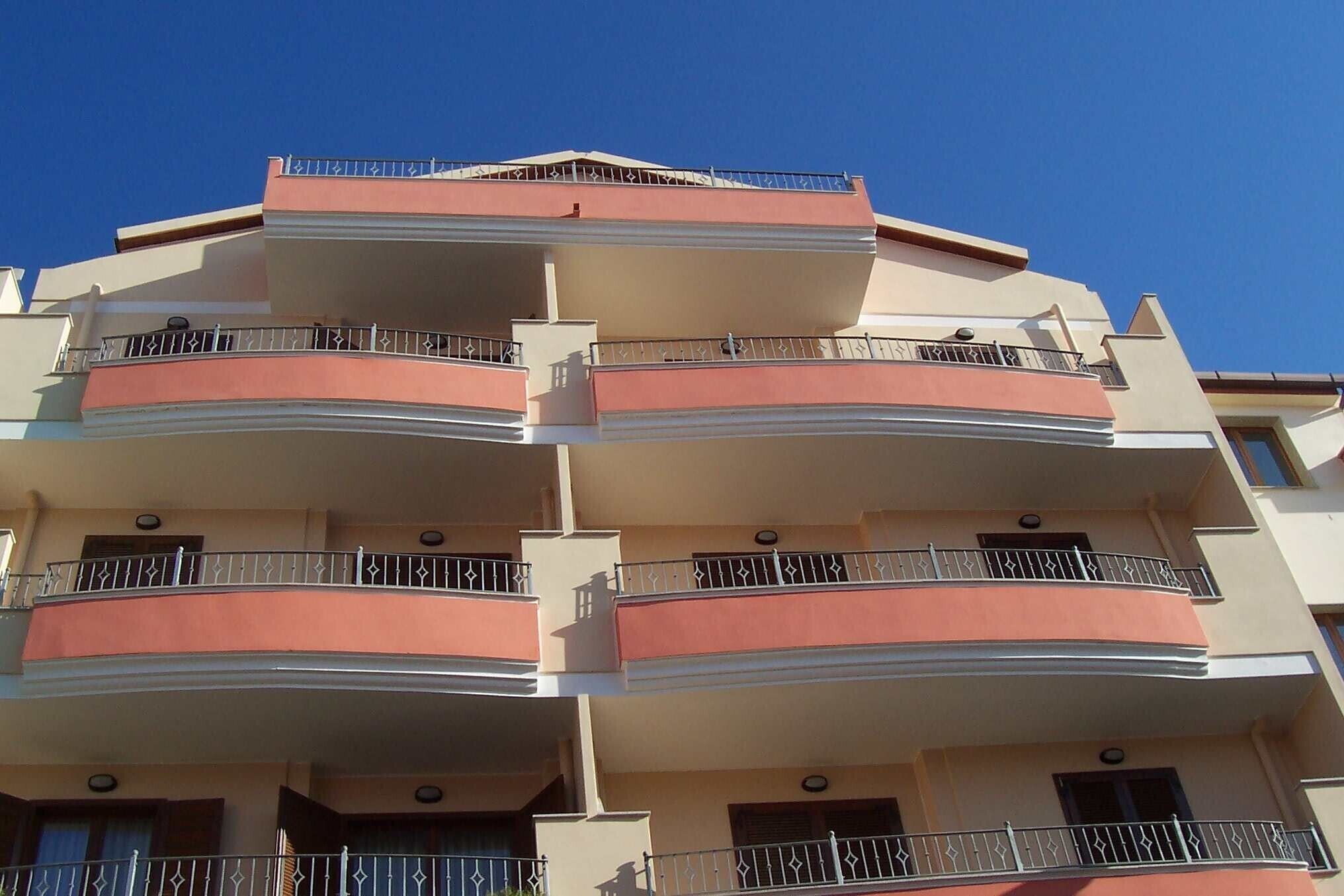 Un edificio residencial de varios pisos con balcones, cada uno con barandillas metálicas y ventanas.