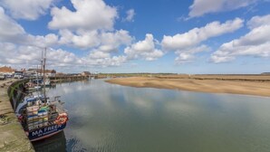 A harbor with a boat named "MA FREEN" docked at a pier, calm water, and a clear sky with clouds. - Kipling House (6), Wells-next-the-Sea, Norfolk (Wells-next-the-Sea)