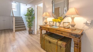 A hallway with a wooden bench, a mirror, and a lamp. There is a staircase in the background. - Kipling House (6), Wells-next-the-Sea, Norfolk (Wells-next-the-Sea)