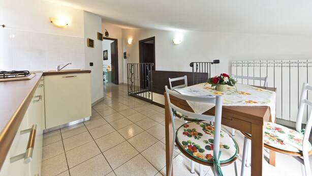 A kitchen with a stove, sink, and cabinets, a dining area with a table and chairs, and a staircase leading to another level. - Poggio RINESCHI -SPINA apartment with pool, Monte Amiata, Maremma (Castel del Piano)