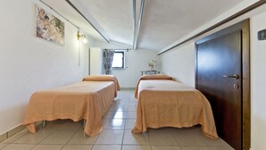 A hotel room with two beds, a wooden door, a window with curtains, and a painting on the wall. - Poggio RINESCHI -SPINA apartment with pool, Monte Amiata, Maremma (Castel del Piano)