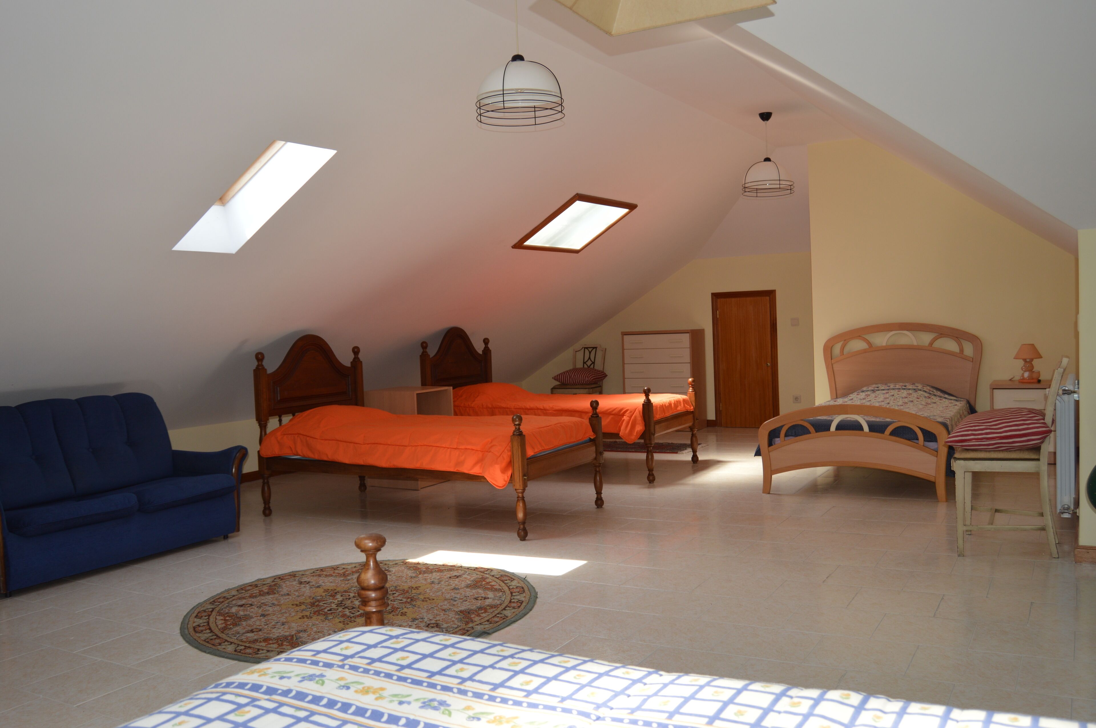 Un dormitorio con dos camas, un sofá y un ventilador de techo.