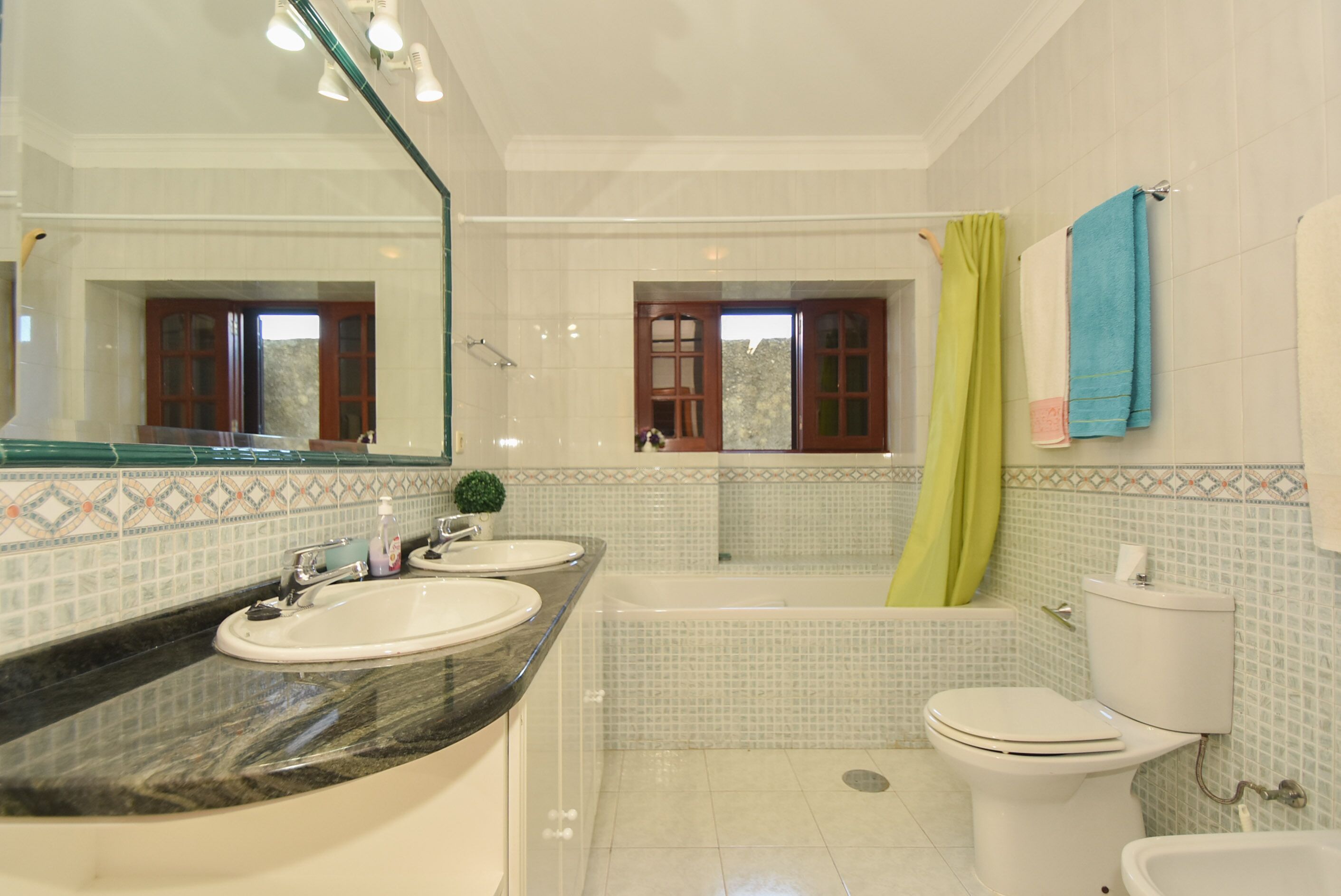 A bathroom with two sinks, a bathtub, and a toilet.