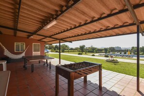 Un patio cubierto con una mesa de fútbol de mesa, una hamaca y una mesa de ping pong.