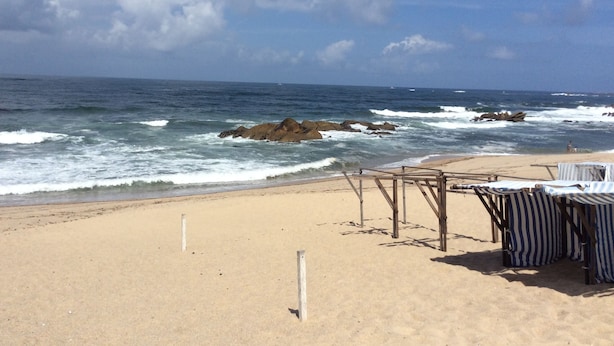 A beach with a wooden structure and striped beach chairs.