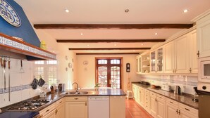 A spacious kitchen with white cabinets, a central island, and a blue stove.