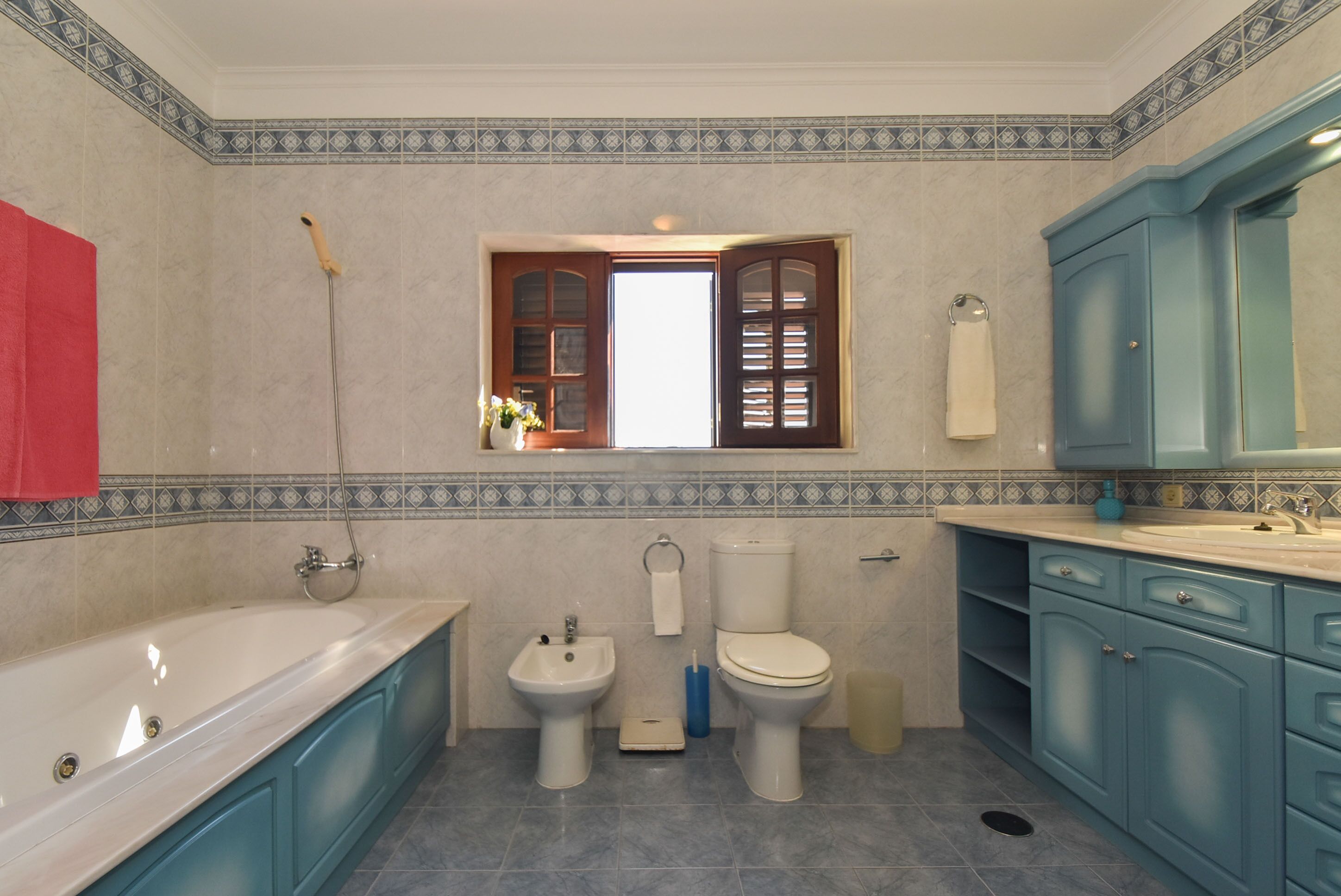 Ein Badezimmer mit Badewanne, Bidet, Toilette und blauen Schränken.