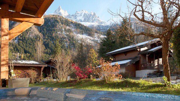 A wooden cabin with a view of snow-capped mountains.