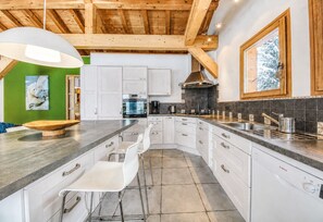 A modern kitchen with white cabinets, a large island, and a Bosch dishwasher. - Chalet Minouche Chamonix (Chamonix-Mont-Blanc)