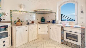 A kitchen with white cabinets, a herringbone floor, a large window, and a view of the sky.