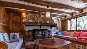 L’intérieur d’un chalet rustique, avec une cheminée en pierre, des meubles en bois et une grande fenêtre.