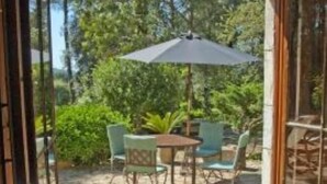 Une terrasse ouverte avec un sol en pierre, une table, des chaises et un parasol.