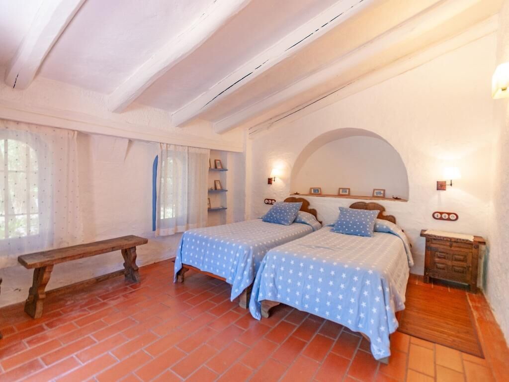 A bedroom with two beds, a bench, and a rustic wooden cabinet.