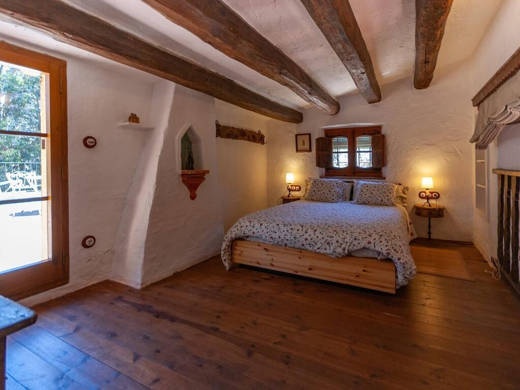 A bedroom with a wooden bed, a window, and a wall-mounted shelf.