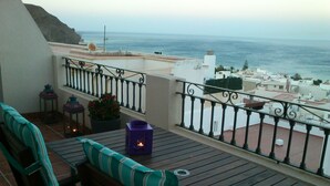 A balcony with a view of the sea, wooden furniture, and a potted plant. - PENTHOUSE in Cabo de Gata with fabulous sea views (Carboneras (Almería))