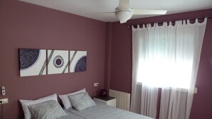 A bedroom with a bed, a ceiling fan, a radiator, and a window with sheer curtains. - PENTHOUSE in Cabo de Gata with fabulous sea views (Carboneras (Almería))