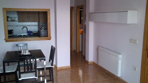 A dining area with a table and chairs, a kitchen visible through a window, and a hallway leading to another room. - PENTHOUSE in Cabo de Gata with fabulous sea views (Carboneras (Almería))