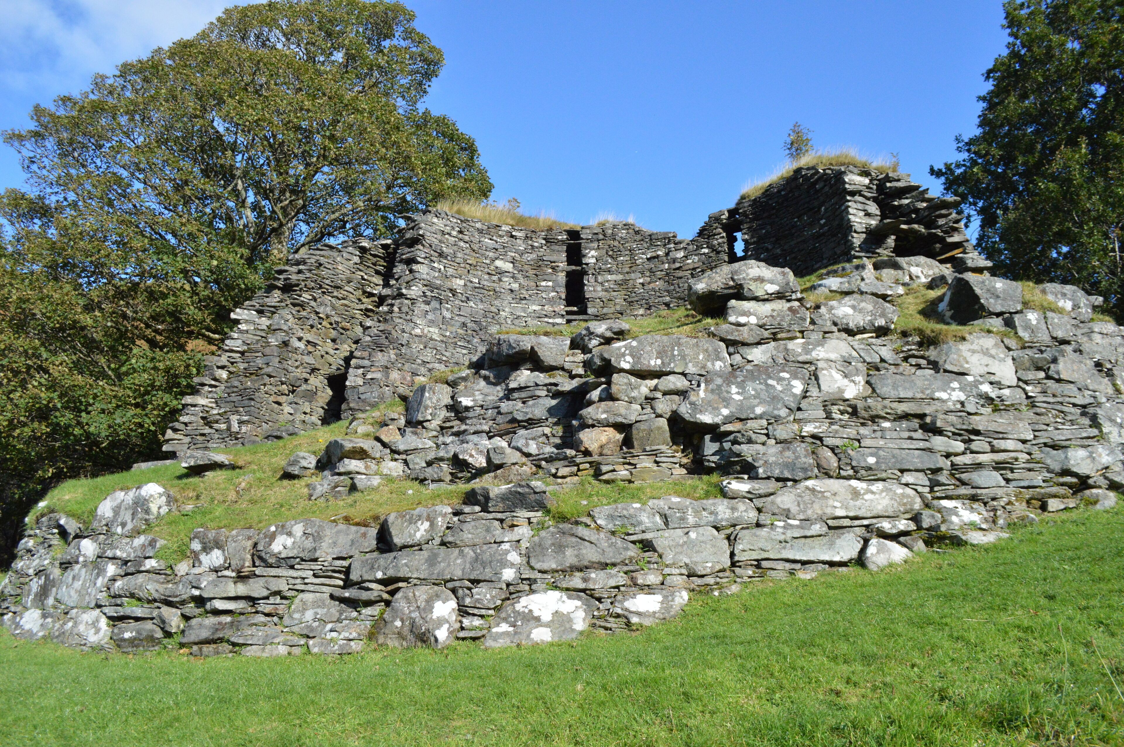 A stone ruin with a partially intact wall and a small opening.