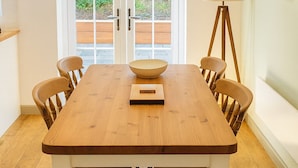 A dining room with a wooden table, chairs, a bowl, and a lamp.
